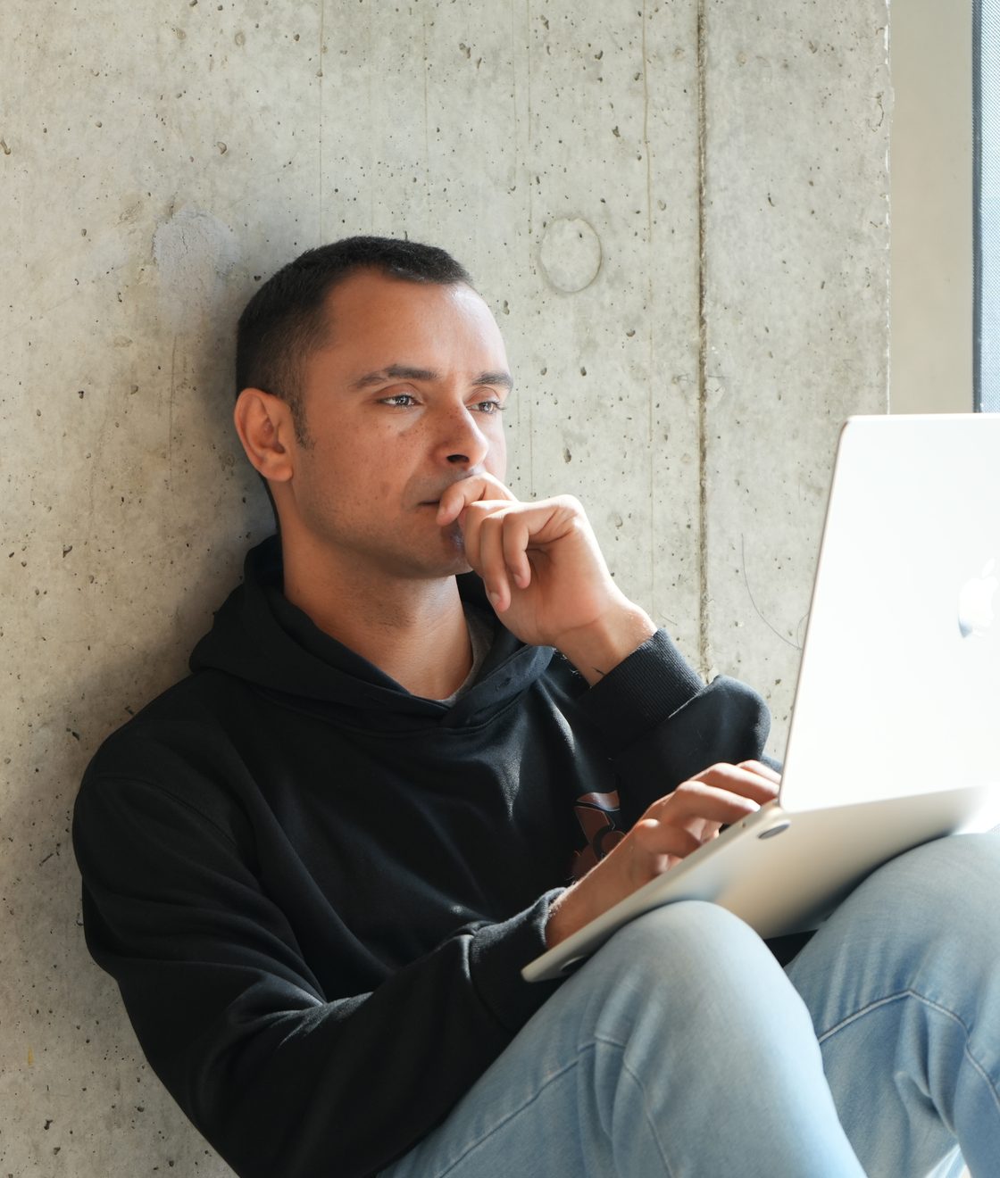 John Patterson, founder of Budulai, working on a laptop against a concrete wall