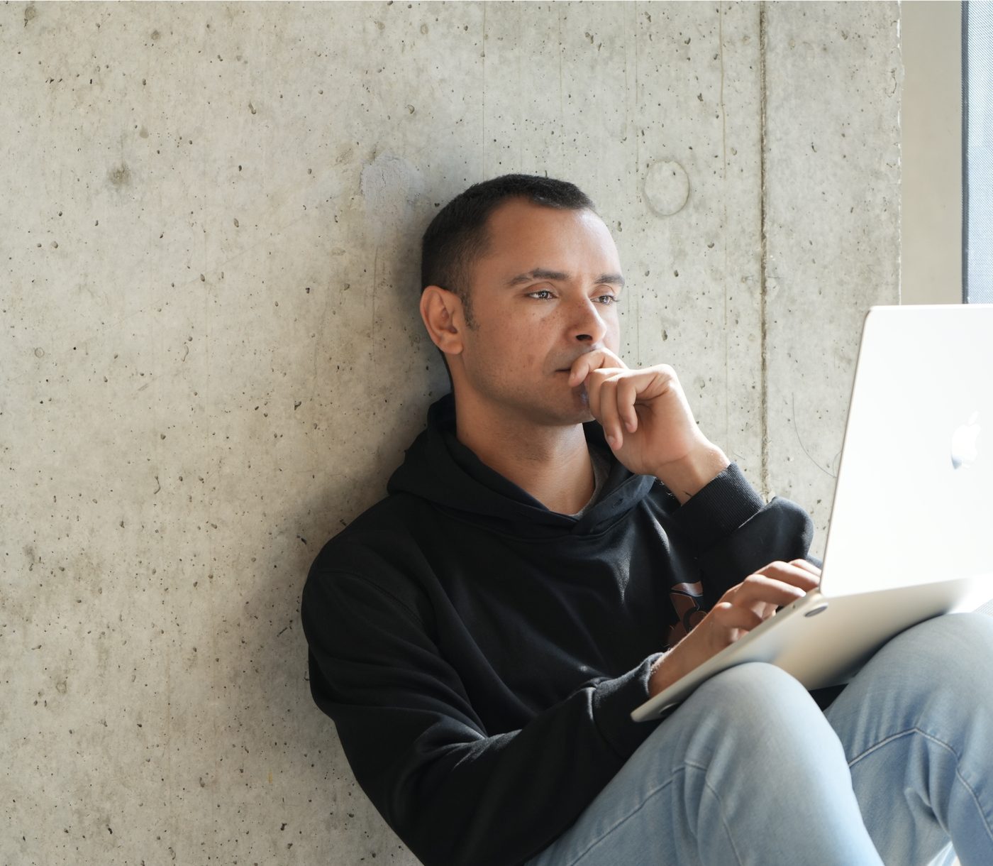 John Patterson, founder of Budulai, working on a laptop against a concrete wall